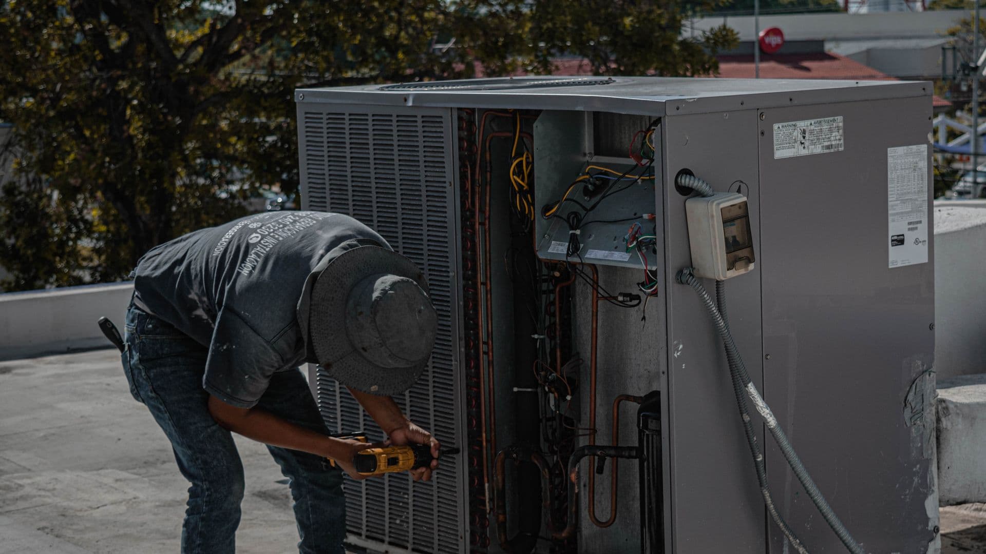 Technician servicing a rooftop packaged air-conditioning unit