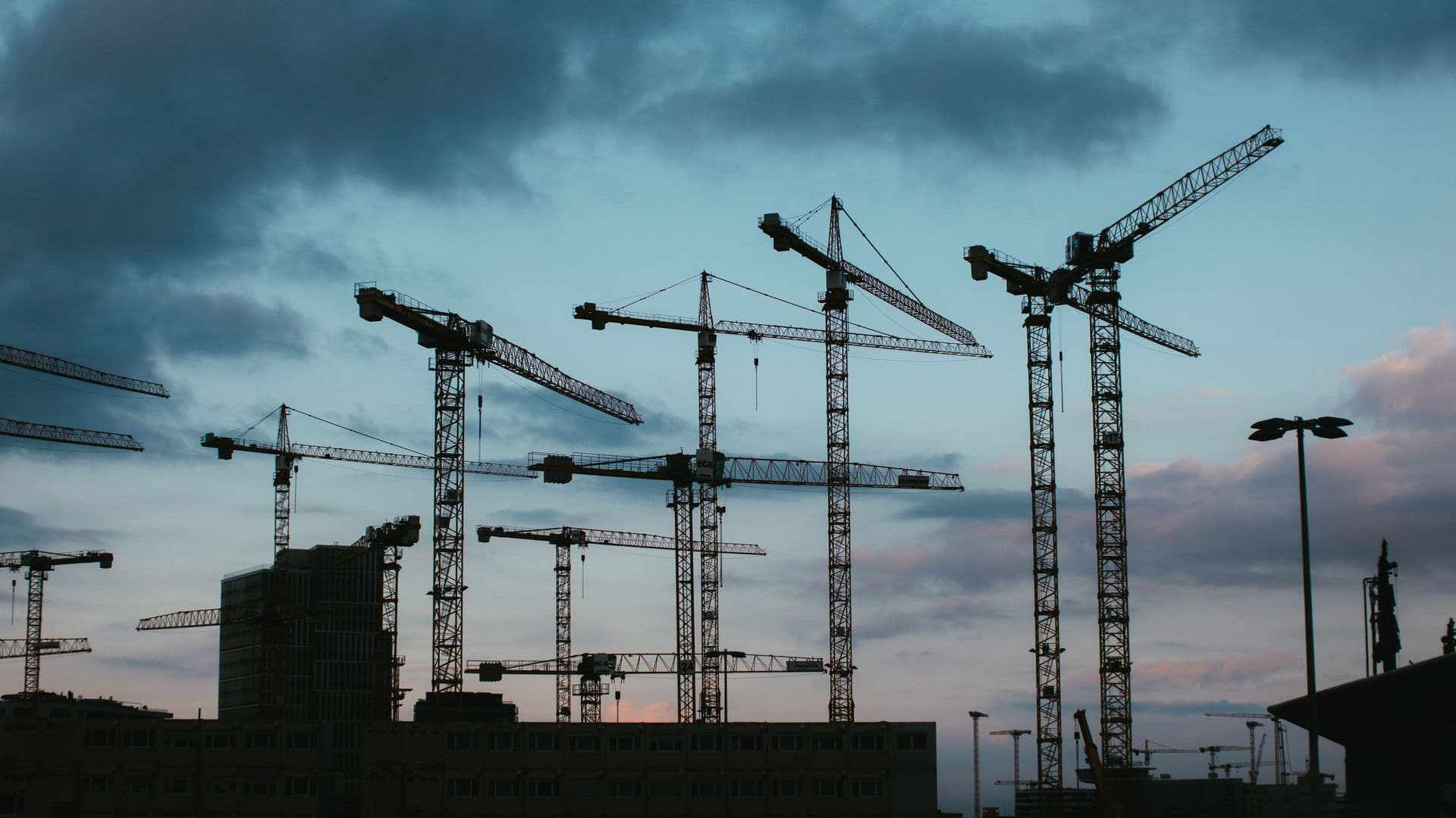 Tower cranes over an active construction site at dusk